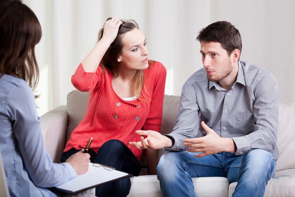 A woman sitting on the couch with two men.